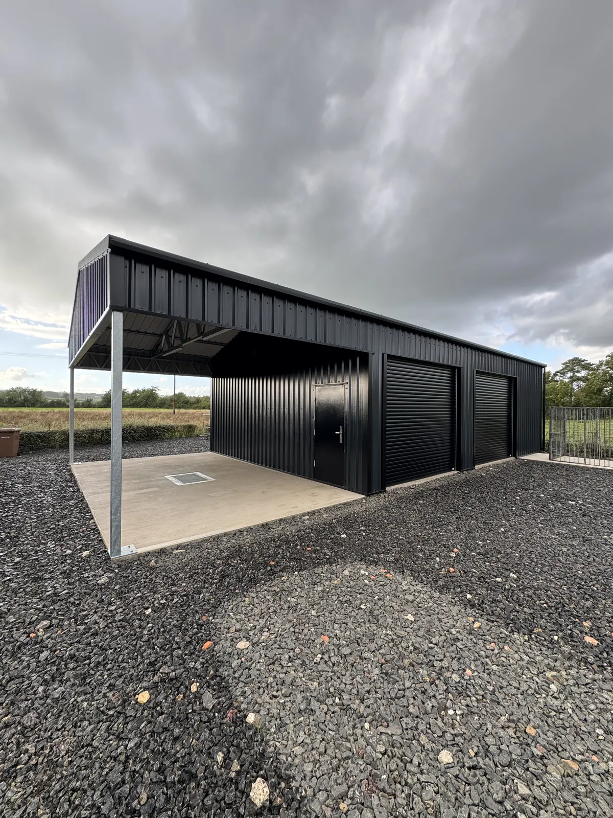 Black steel building with roller doors and a covered canopy